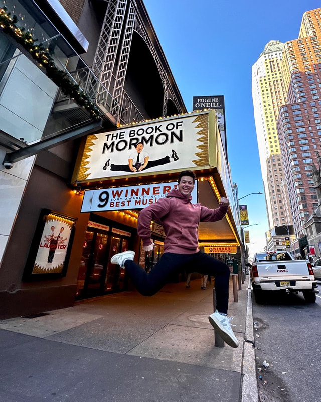 Tony Moreno jumping in front of Book of Mormon marquee
